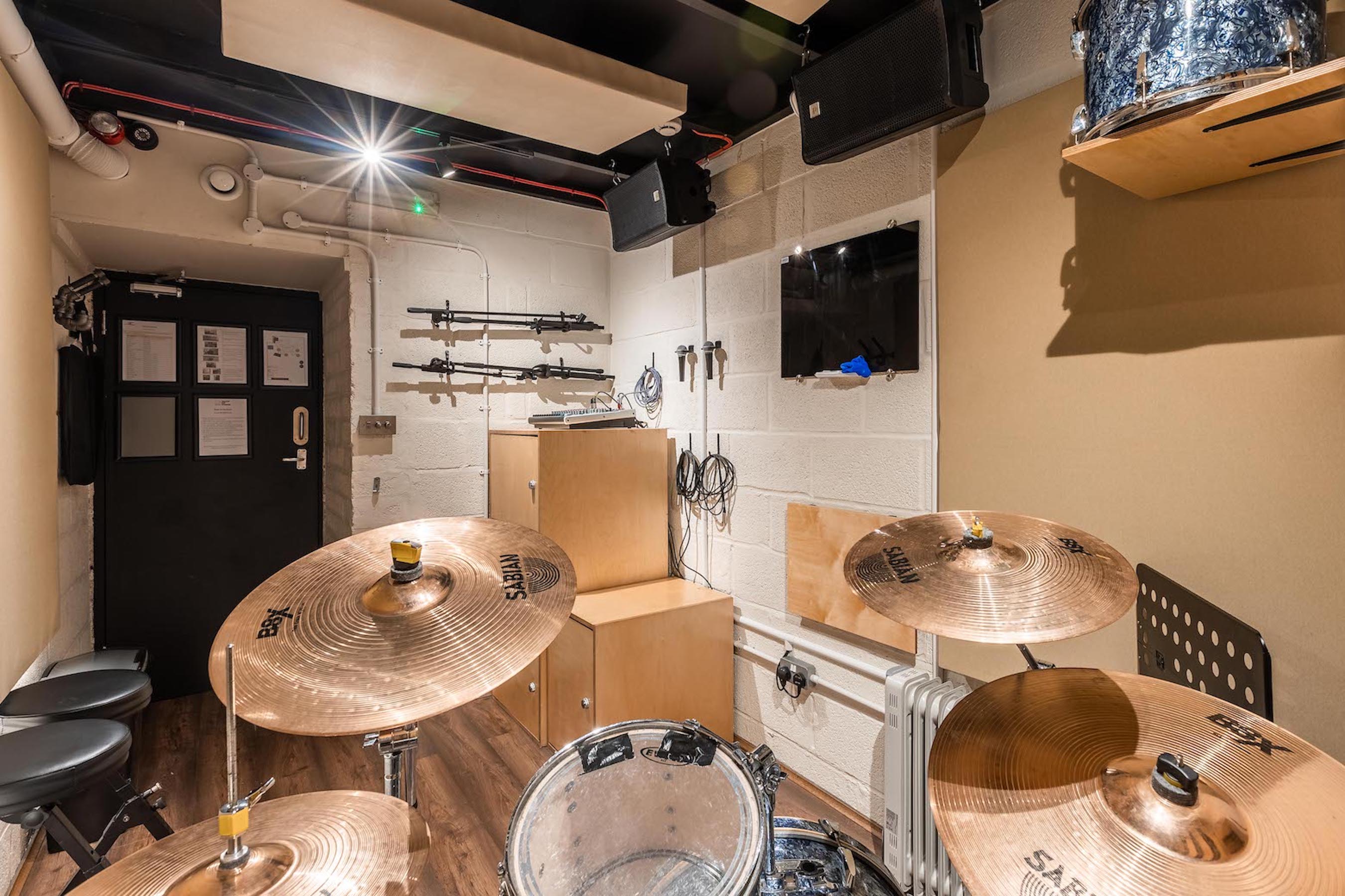 Yellow Hat Studios rehearsal space with drum set, ideal for music workshops and performances.