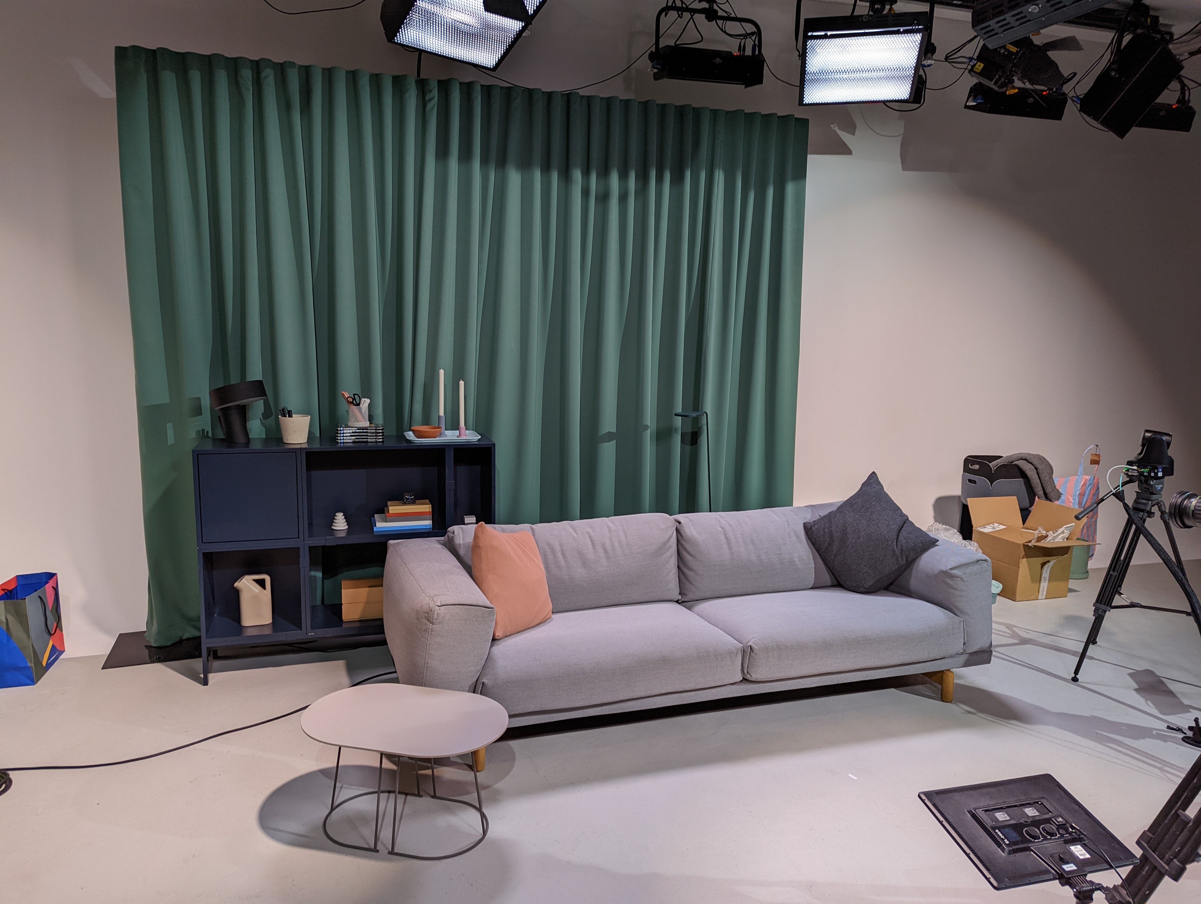 Modern meeting space with sofa and green curtain, perfect for virtual events and brainstorming.