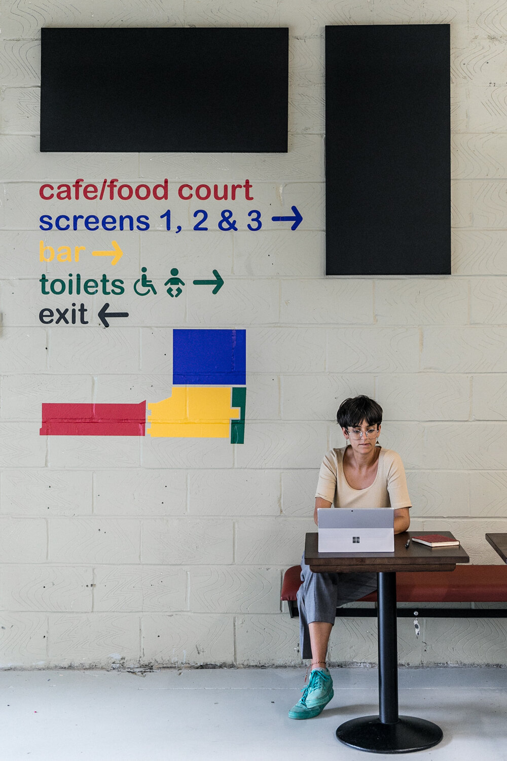 Woman working on laptop in Catford Mews Foyer, ideal for events and meetings.
