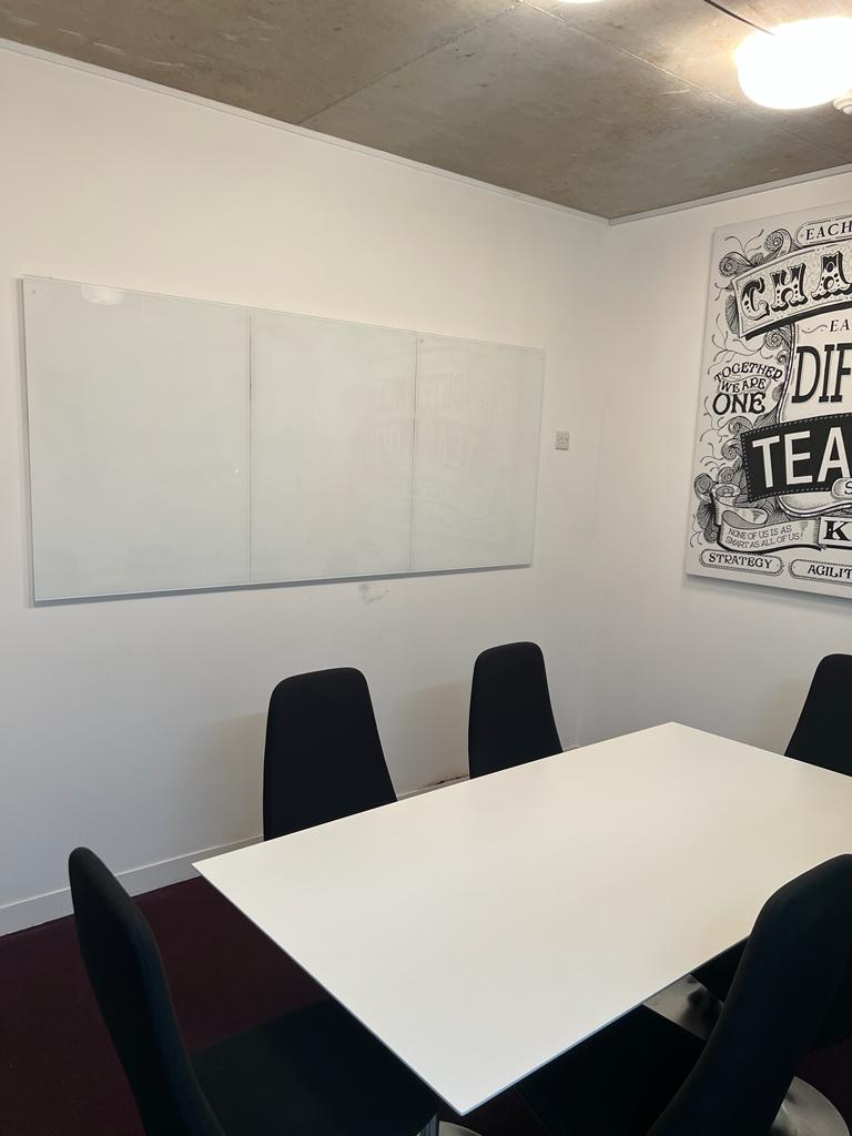 Minimalist meeting room with whiteboard and sleek table for brainstorming sessions.