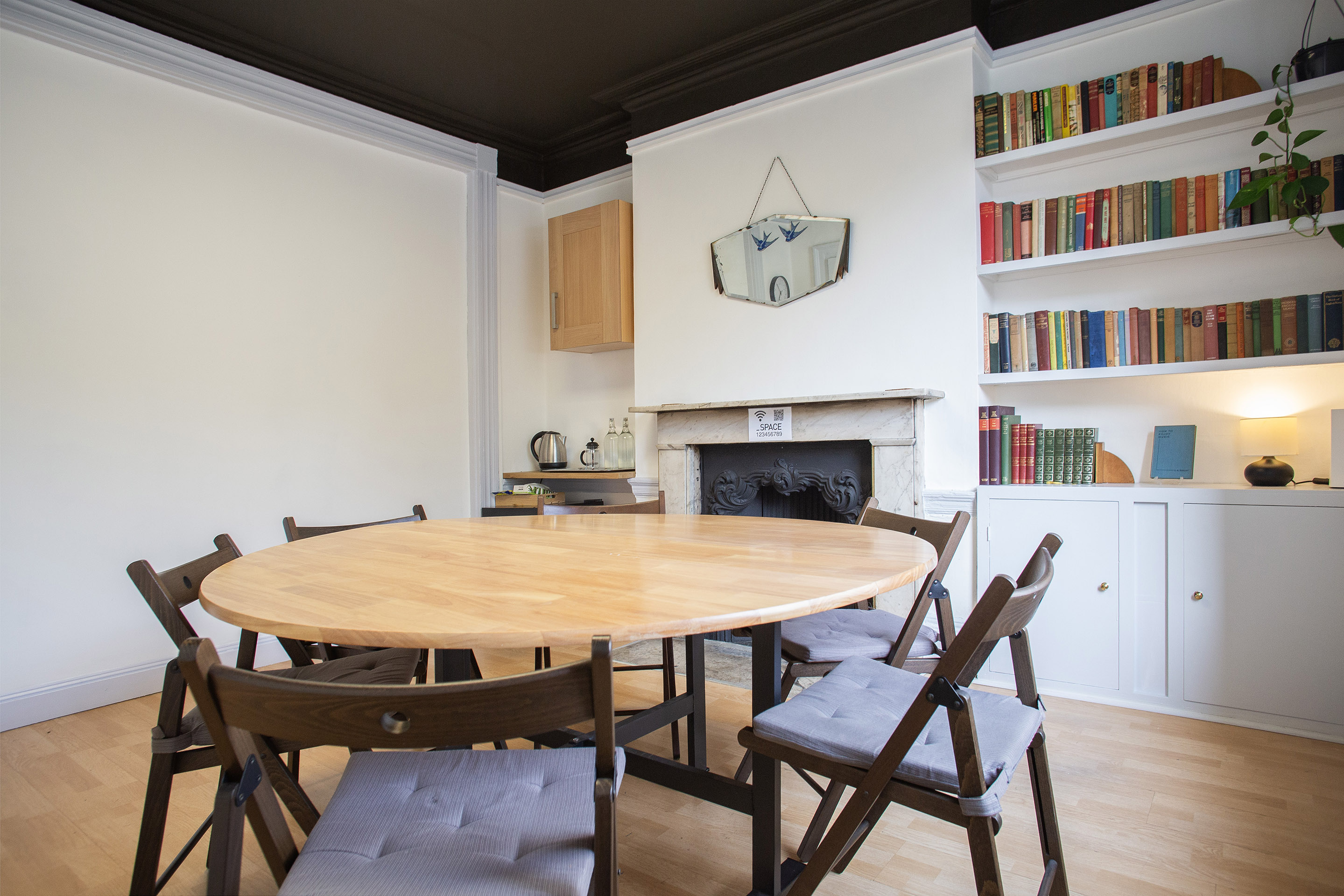 Cozy meeting space with round wooden table for workshops and brainstorming sessions.