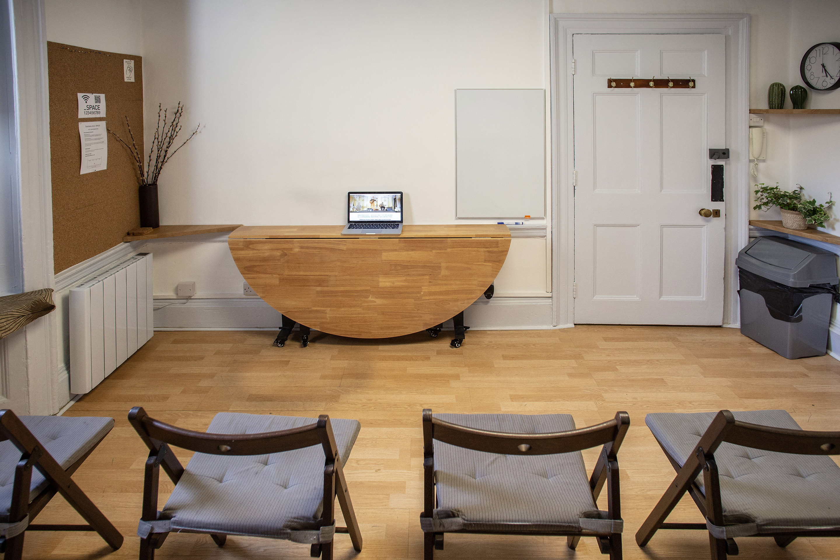 Minimalist meeting space with central table and laptop for workshops or team discussions.