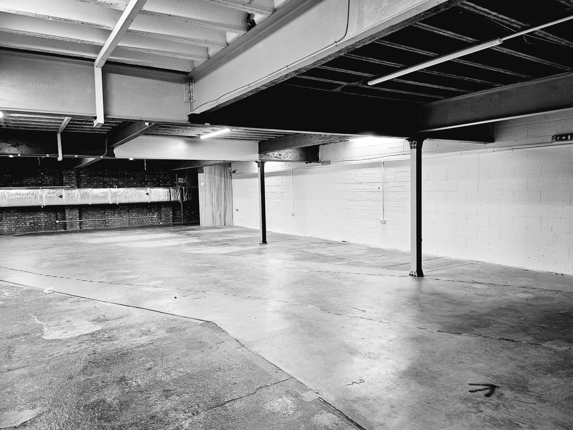 Spacious industrial venue with exposed beams for corporate events and social gatherings.
