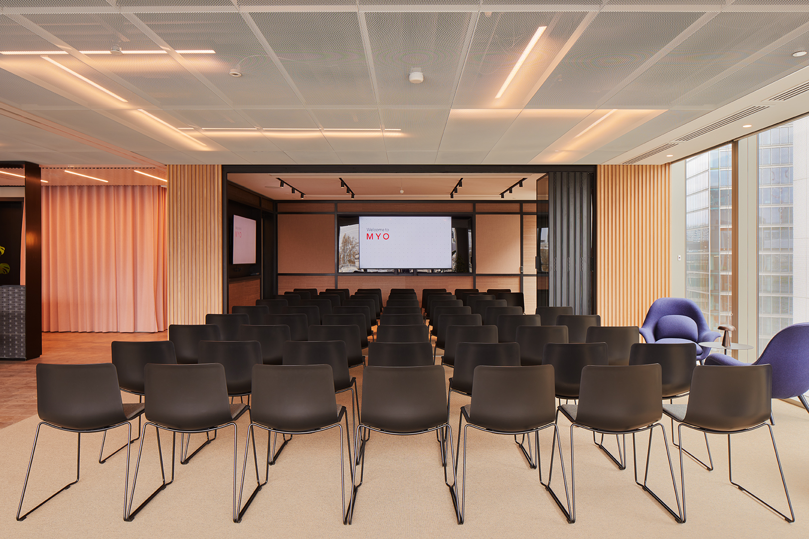 Modern event space with black chairs and large screen for presentations in Myo Liverpool Street.