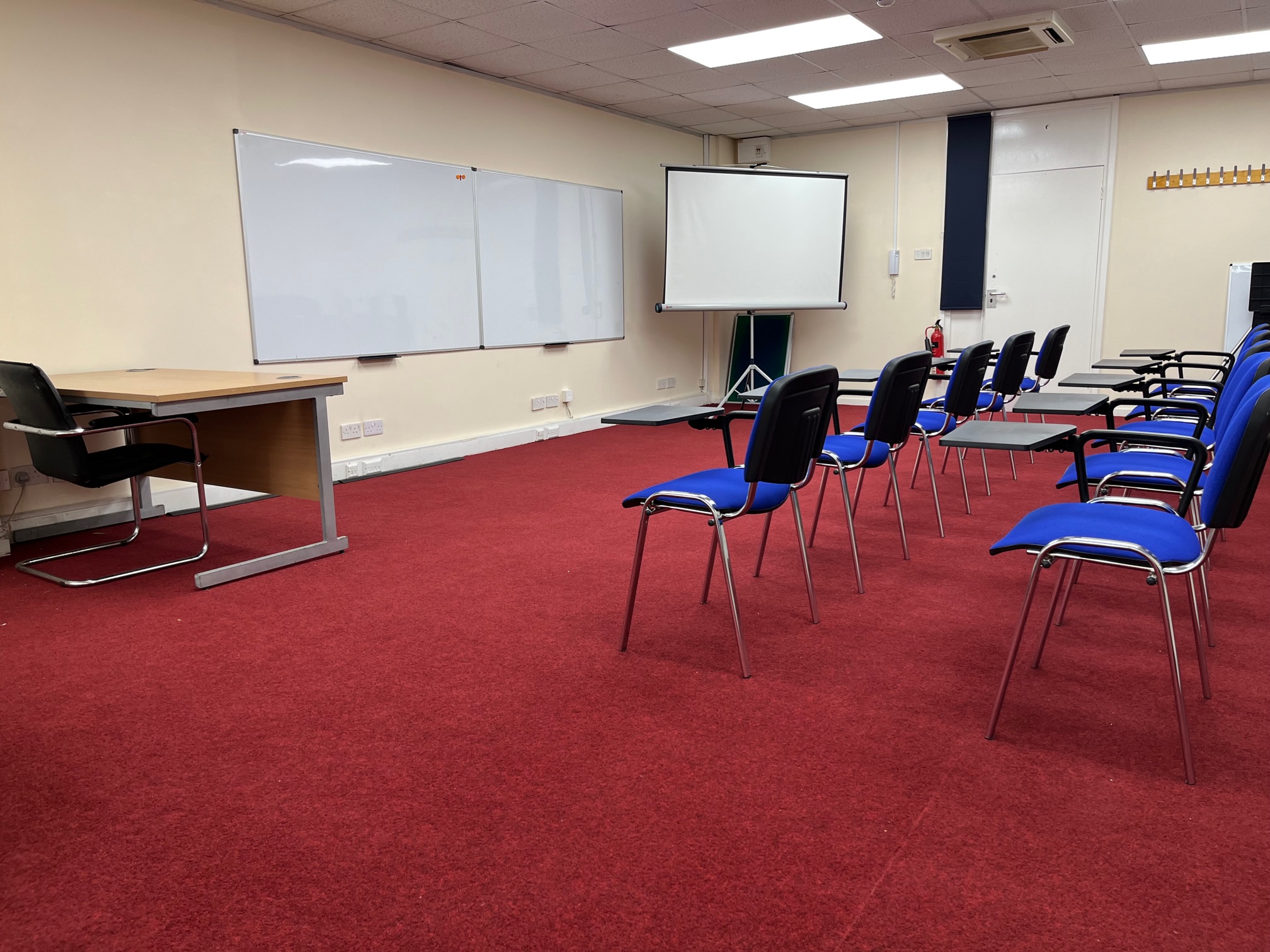 Training room in Whitechapel with blue chairs and presentation screen for workshops.