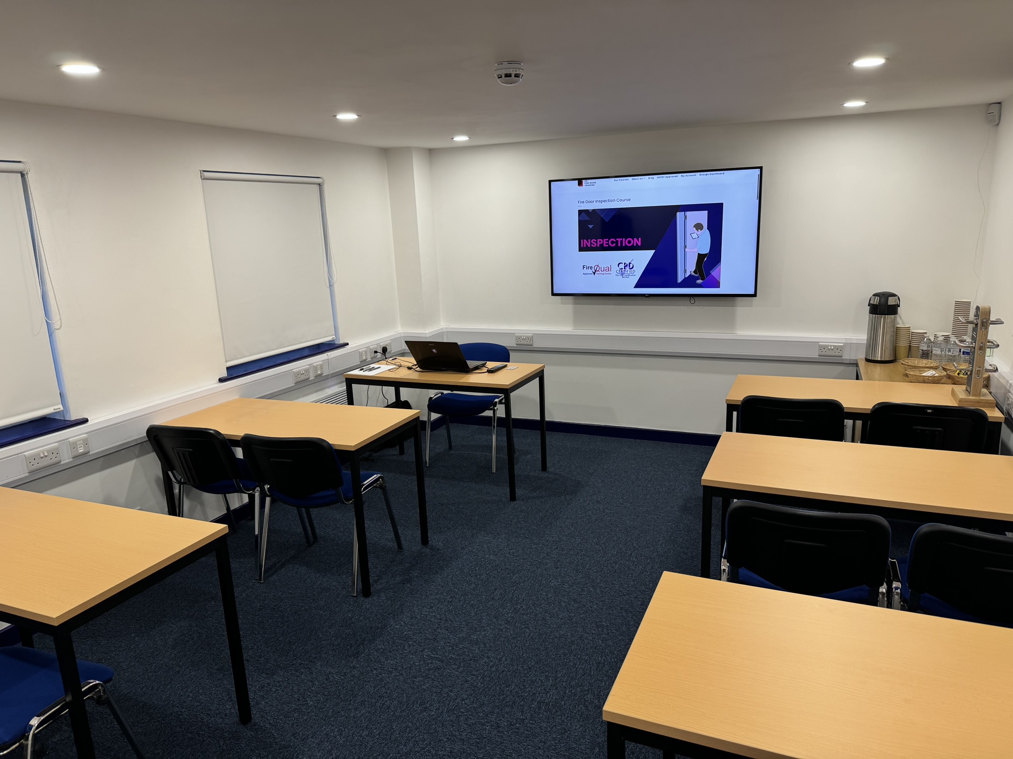 Meeting room setup for training session with large screen and collaborative tables.
