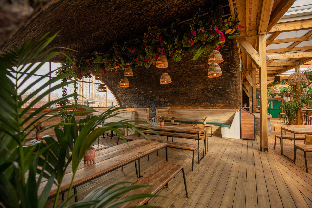 Stylish event space with wooden benches and greenery at The Arches, Pergola Brixton.
