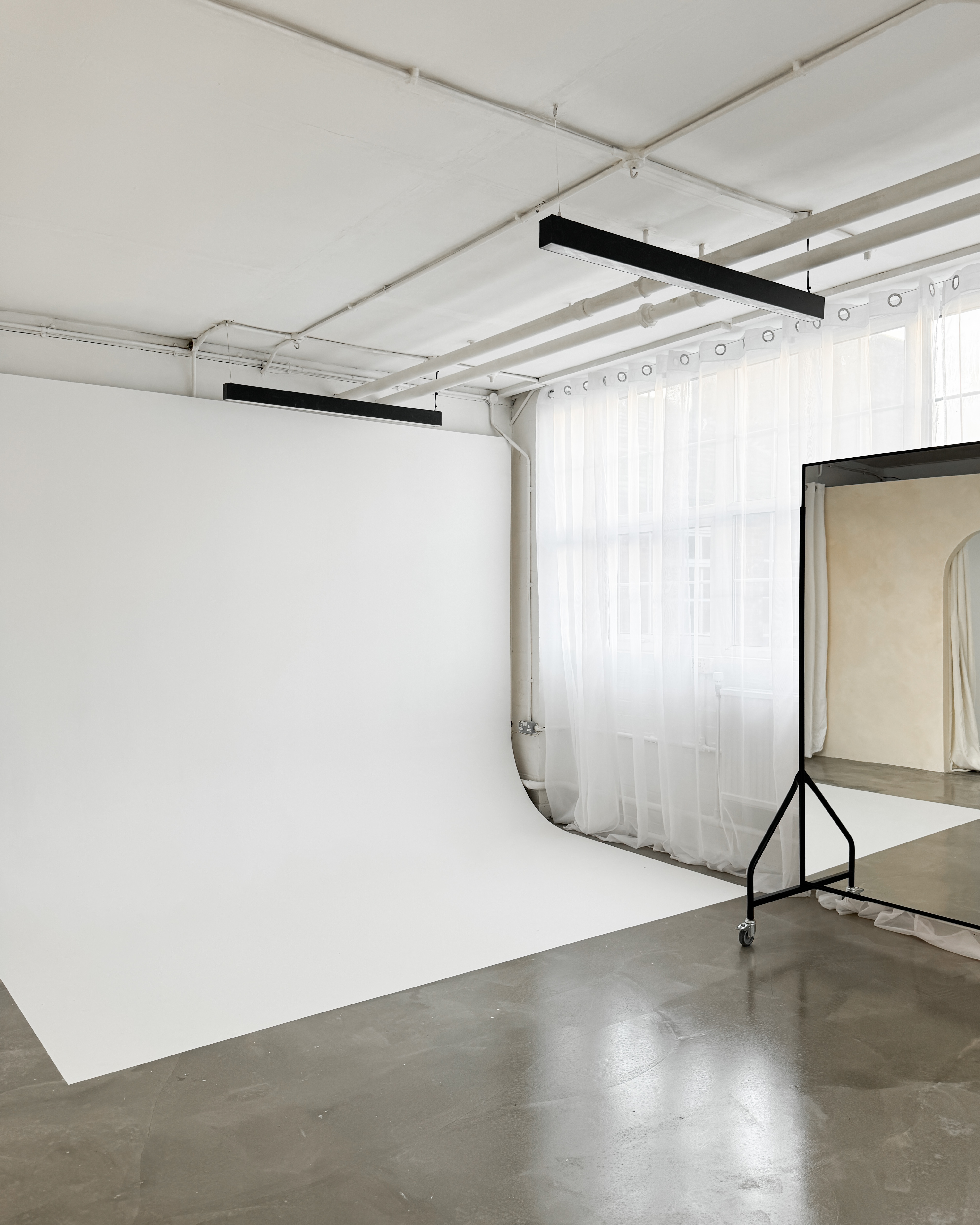 Versatile event space with white backdrop and natural light for workshops and photo shoots.