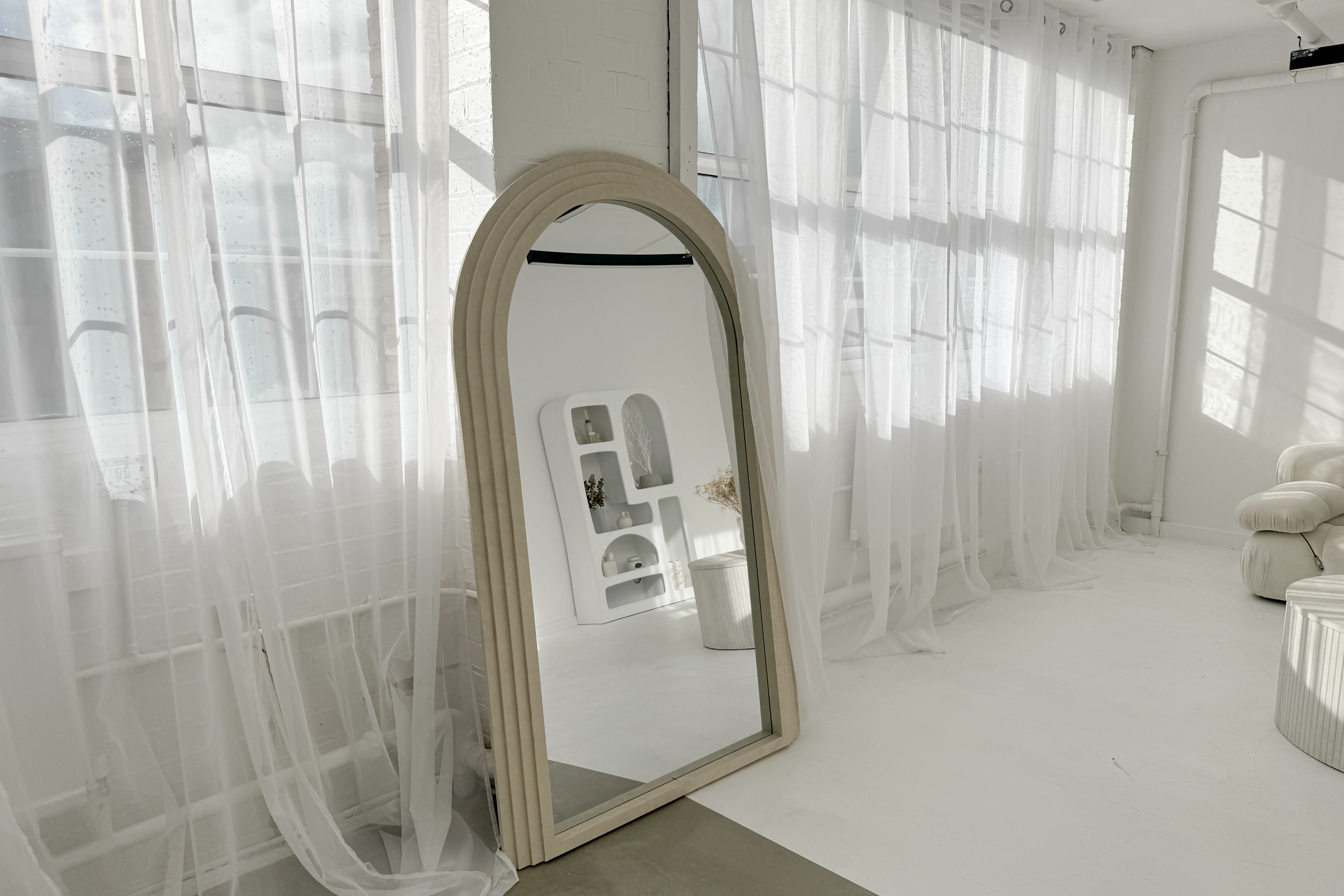Bright event space with large windows and elegant arch mirror at Sumei Studios.
