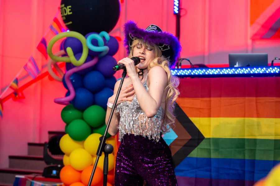 Vibrant performer at LGBTQ+ event in Dugdale Arts Centre with colorful backdrop.