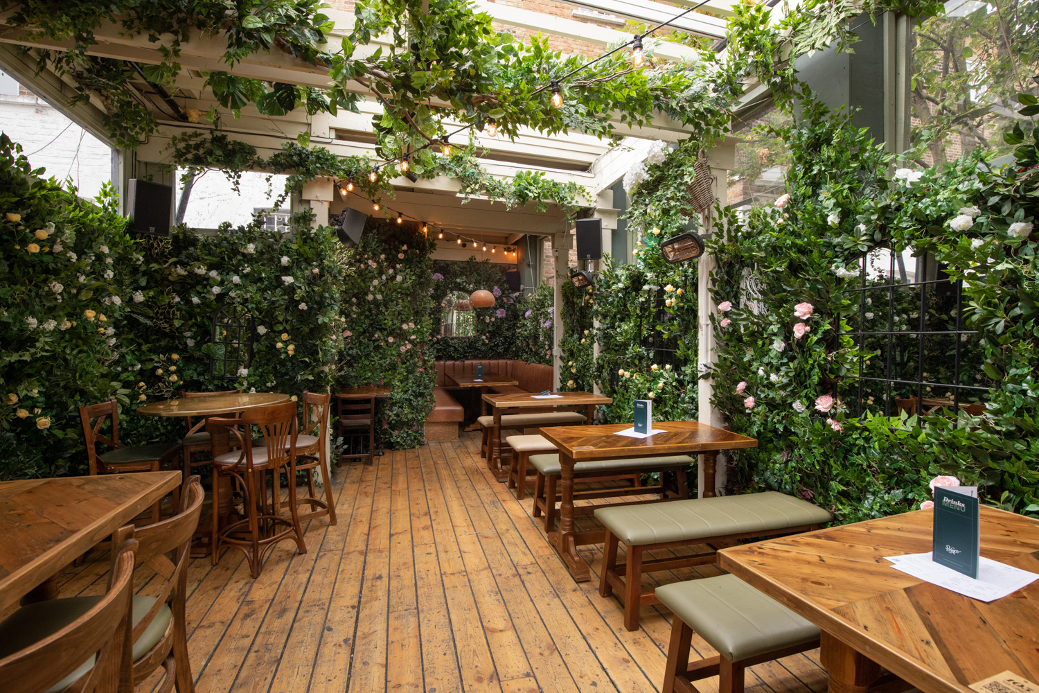 Lush garden event space with wooden tables, perfect for intimate gatherings and meetings.