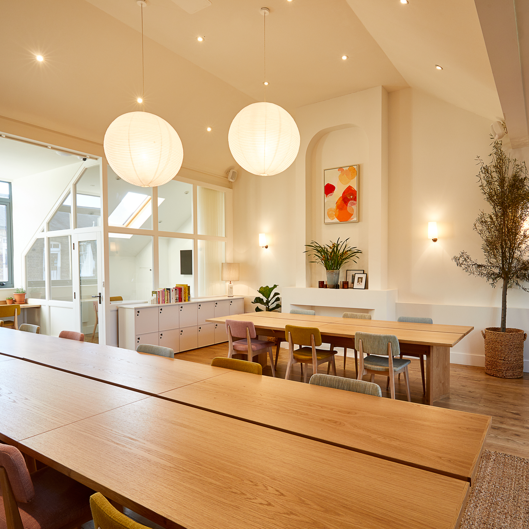 Bright meeting space with wooden table and colorful chairs, perfect for workshops.
