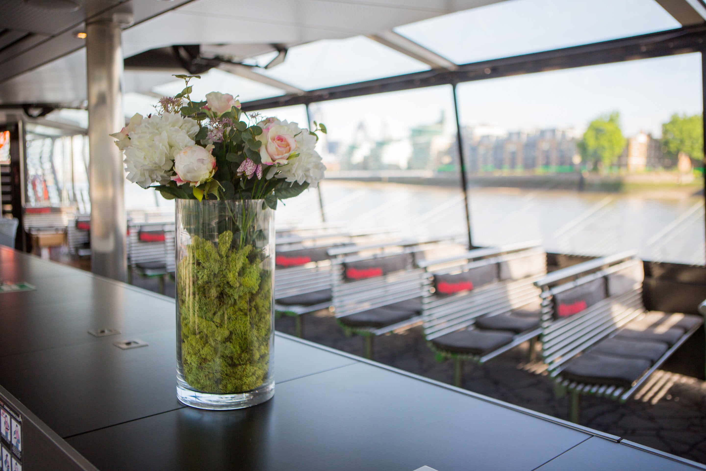 Stylish boat event space with sleek bar and floral decor for corporate gatherings.