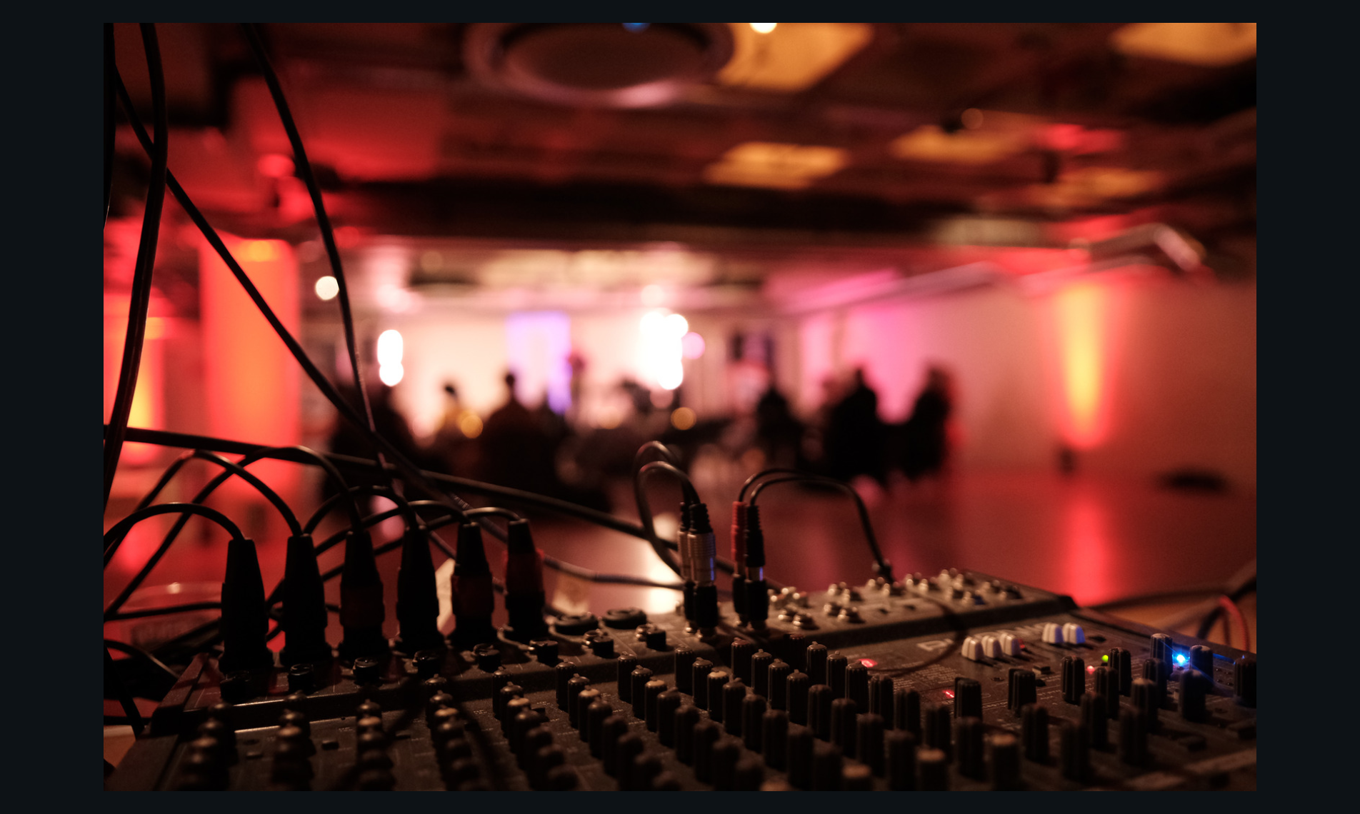 "FUSEBOX Kingston event setup with sound mixing console and engaged audience ambiance."