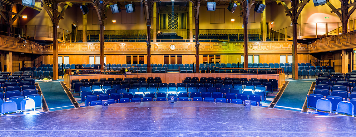 Under-balcony event space with tiered seating, ideal for conferences and performances.