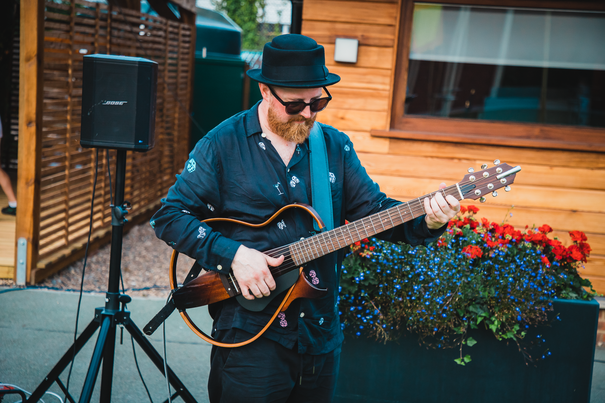 Musician performing at outdoor event in Parson Lawns, vibrant atmosphere with flowers.