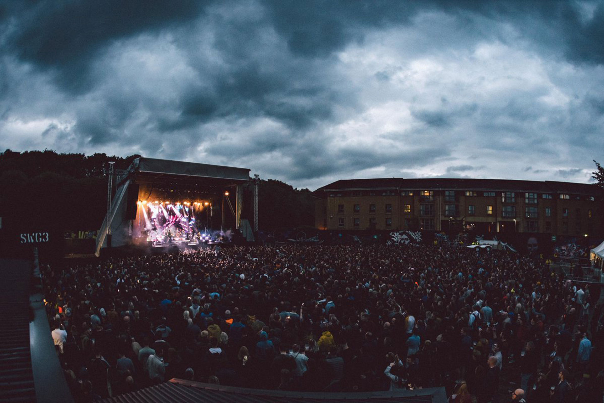 Outdoor event at SWG3 Garden with a packed audience enjoying a live performance.
