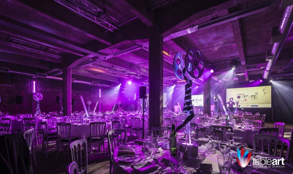 Stylish gala dinner setup in SWG3 warehouse with elegant tables and purple lighting.