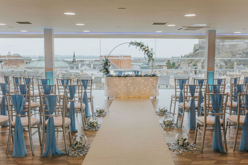 Rooftop terrace wedding venue with elegant blue-accented chairs and floral decor.