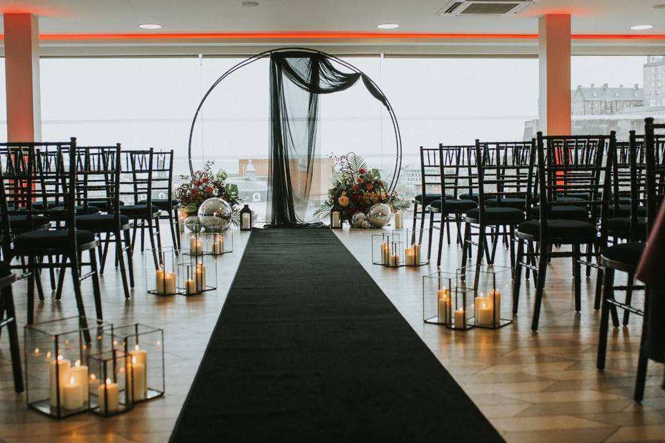 Rooftop terrace wedding setup with black aisle runner and elegant floral arrangements.