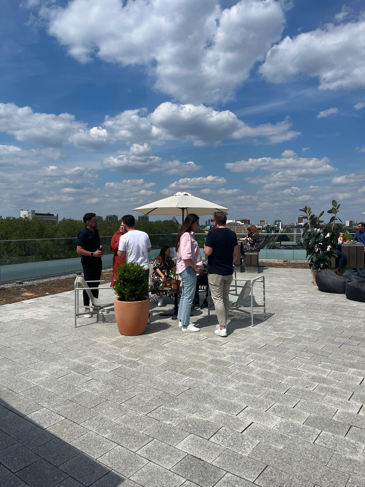 Outdoor terrace networking event in Shoreditch Exchange with stylish umbrellas and greenery.