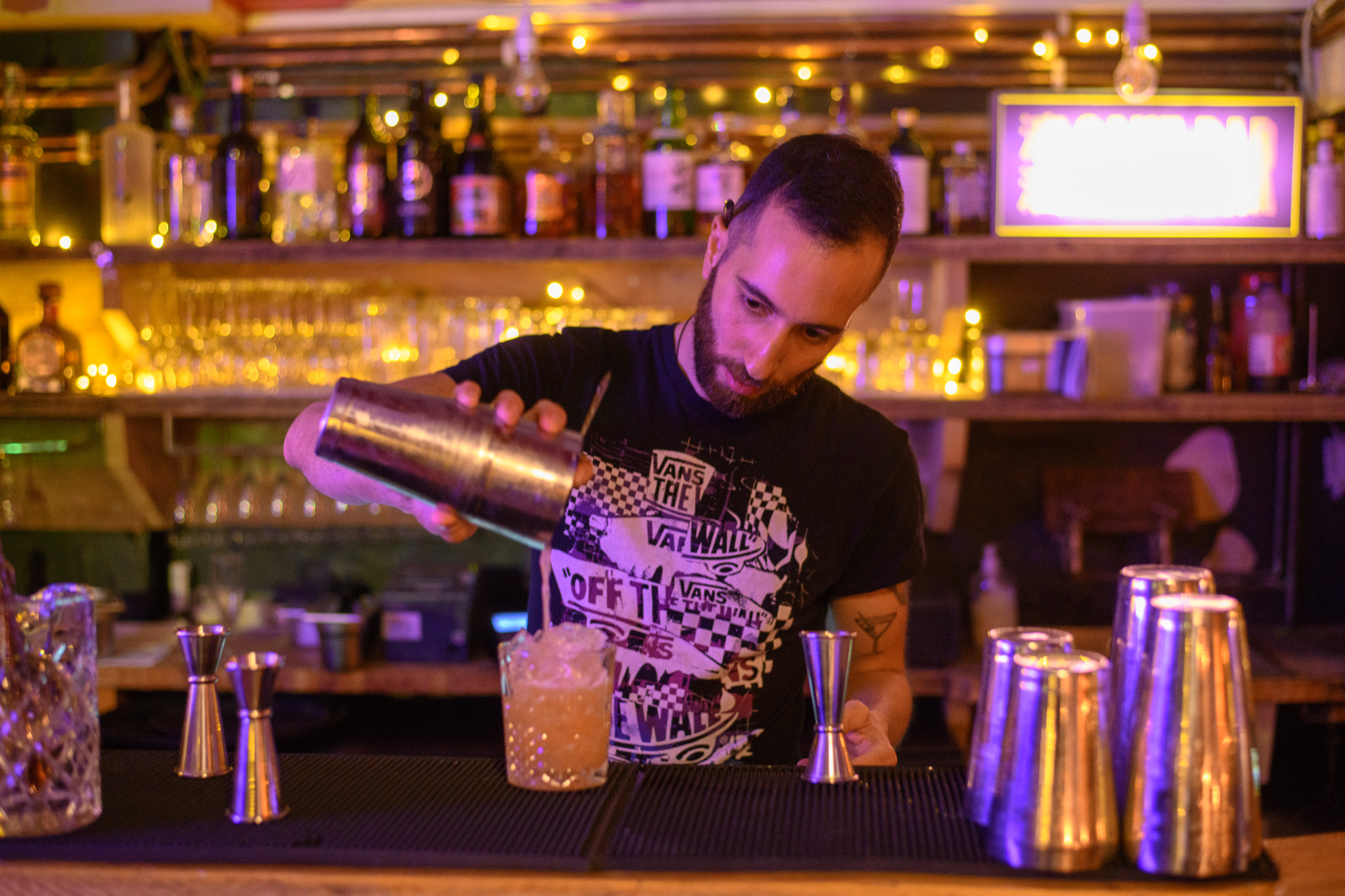Bartender mixing cocktails in vibrant Hanging Garden Room bar for social events.