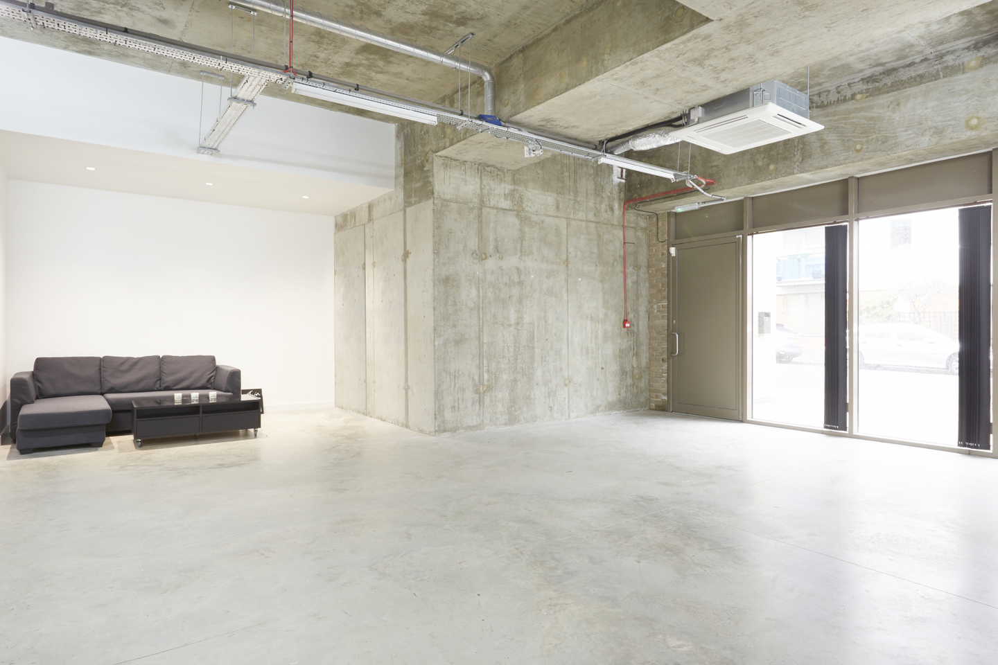 Minimalist event space with concrete walls, ideal for workshops and gatherings.