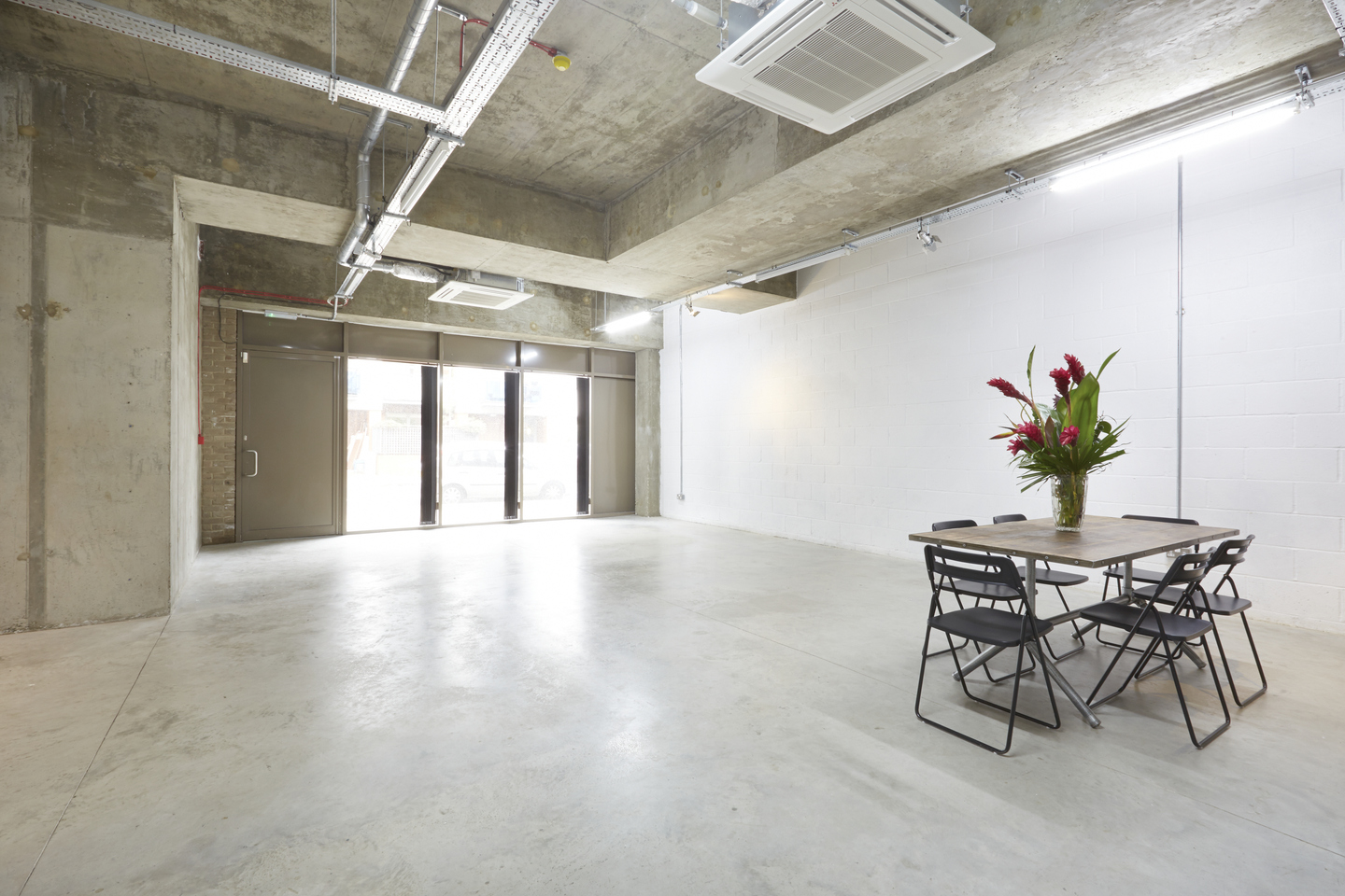 Versatile event space with concrete walls, ideal for workshops and gatherings.
