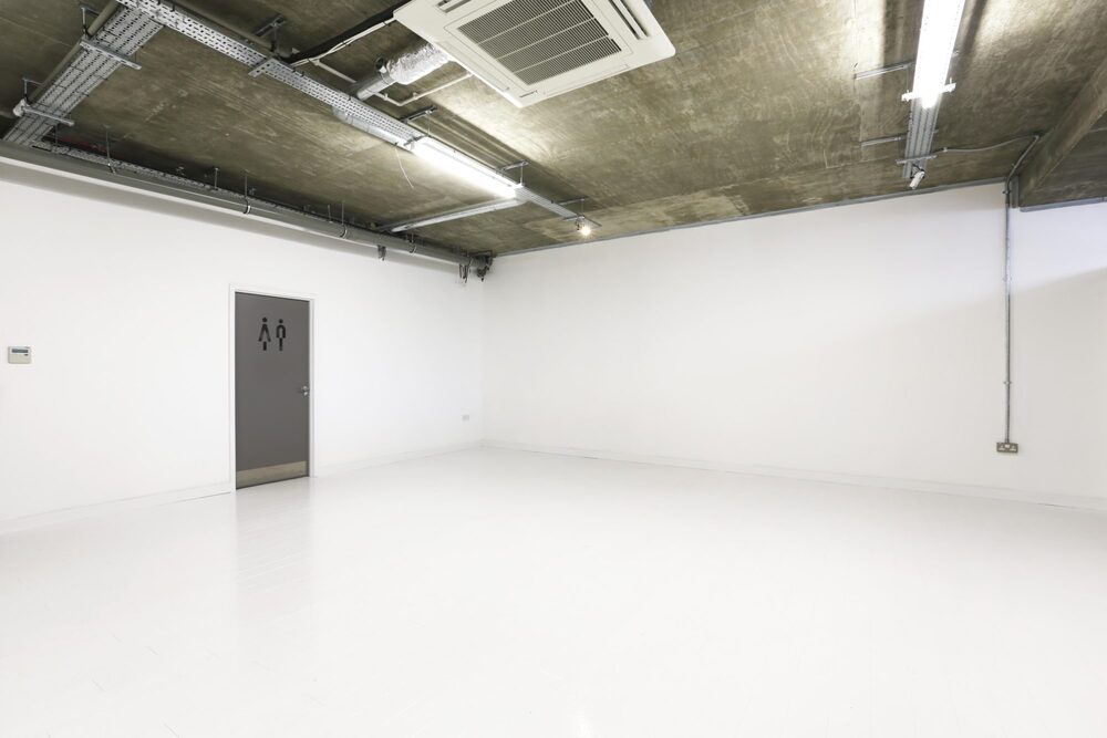Versatile minimalist event space with white floor, ideal for workshops and exhibitions.