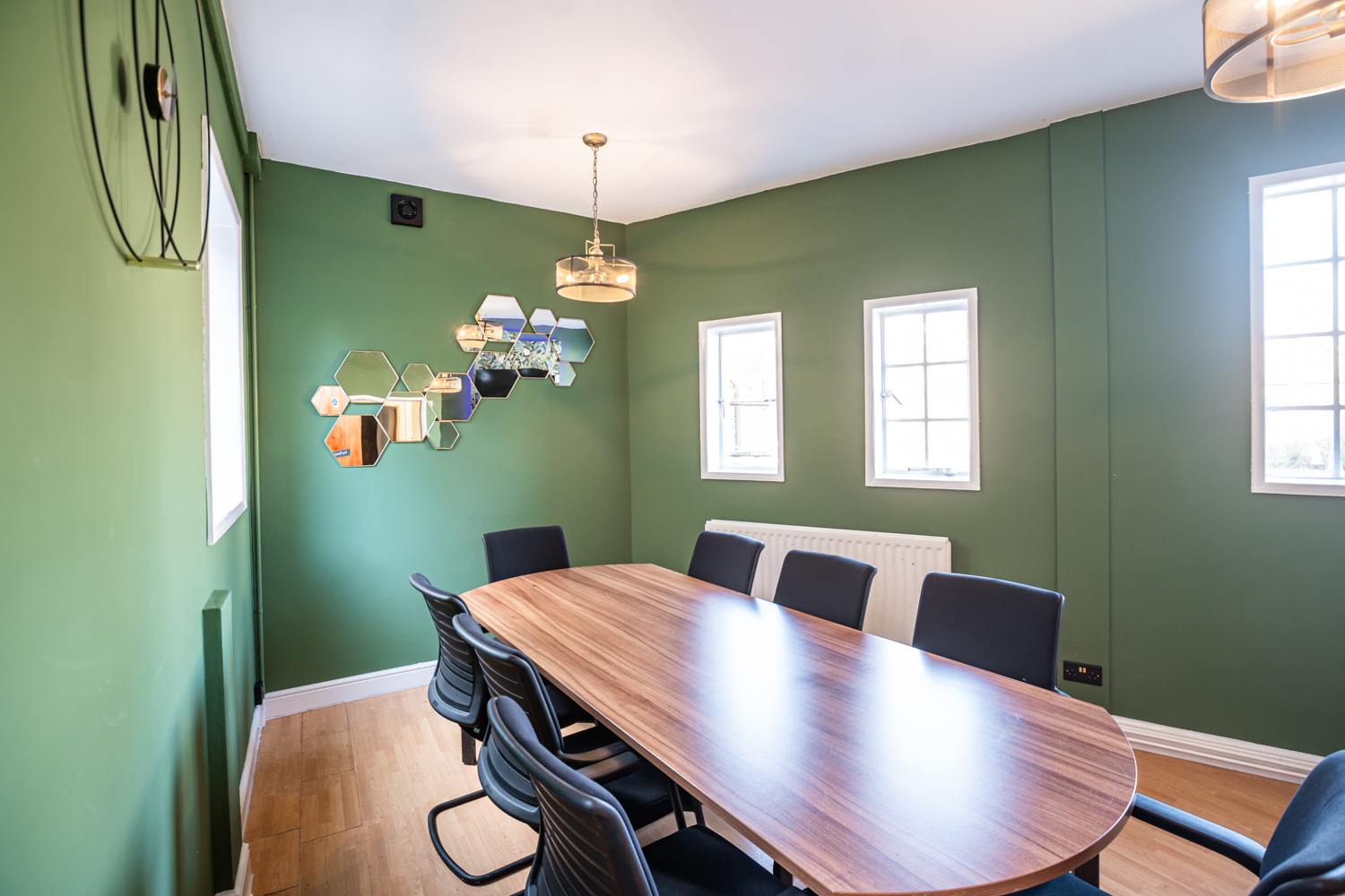 Modern meeting room in Conway Hall with wooden table and green walls for events.
