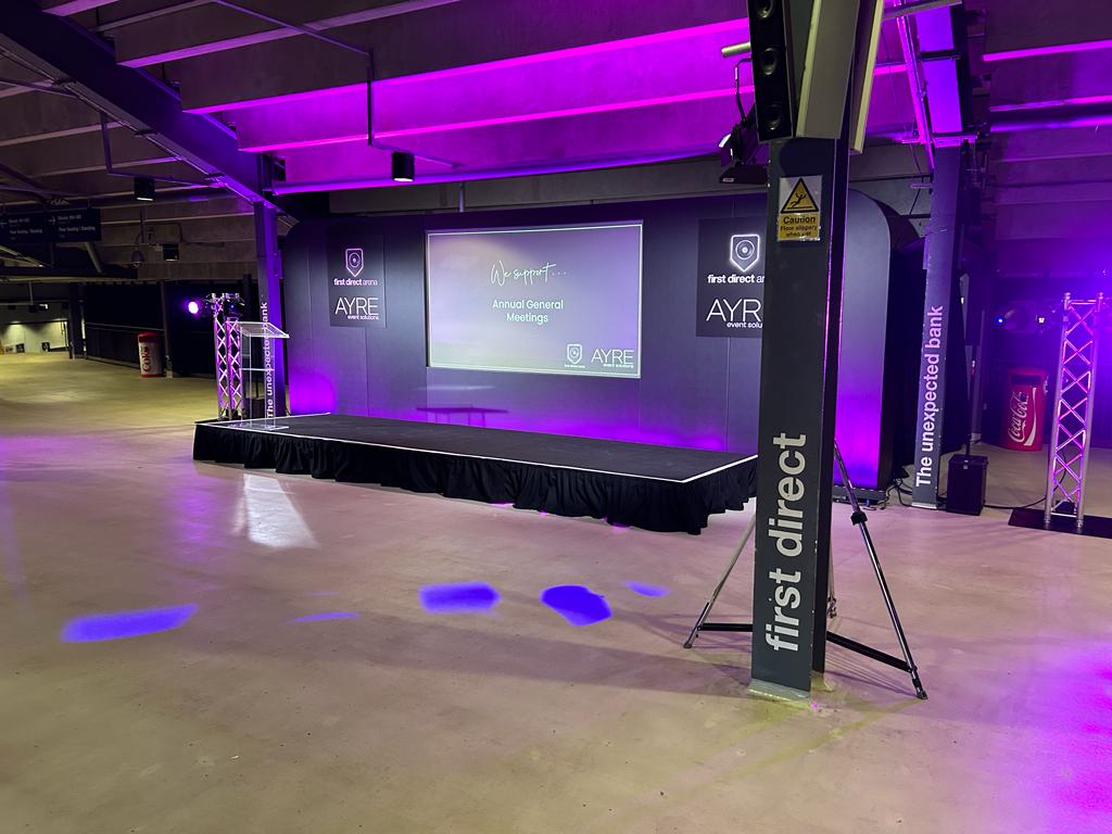 "First Direct Arena Leeds event space with sleek stage and professional lighting for conferences."
