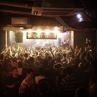 Vibrant crowd in La Belle Angele's Main Room at a lively event, showcasing engagement and energy.