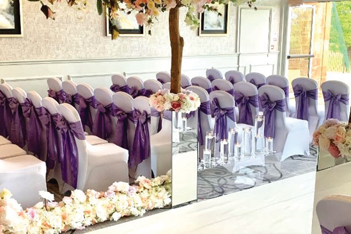 Elegant wedding event space with white chairs and purple sashes, perfect for ceremonies.