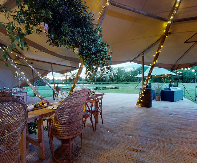 Outdoor tipi event space with string lights, rustic tables, perfect for celebrations.