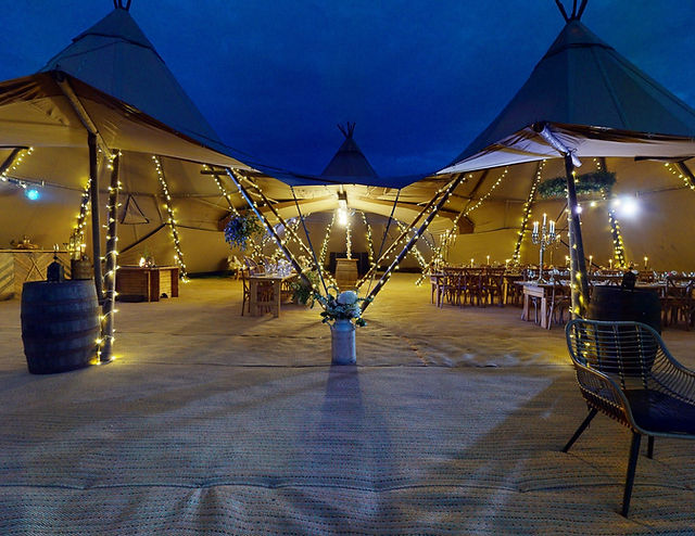 Outdoor tipi event space with soft lighting, perfect for weddings and corporate gatherings.