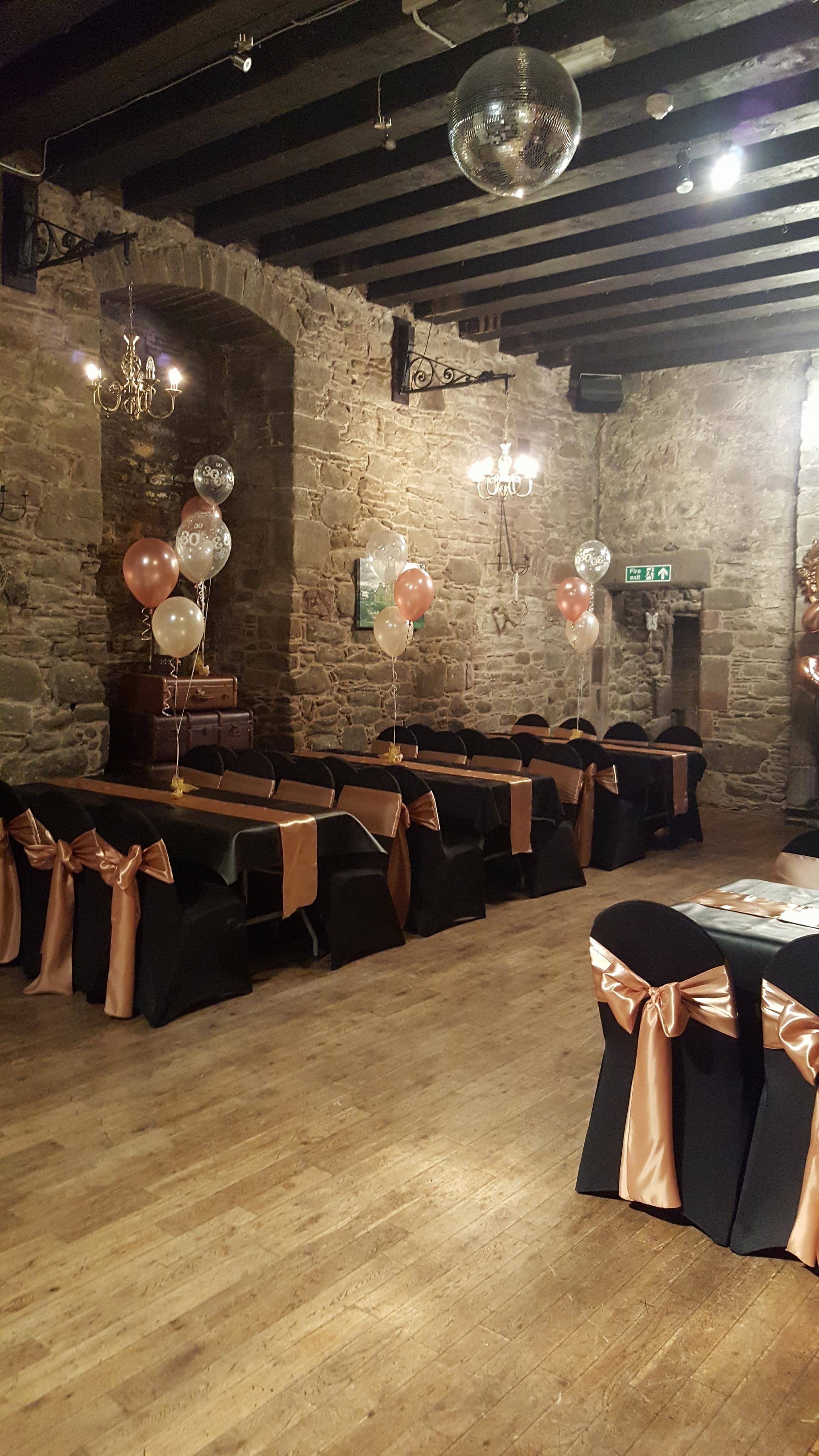 Elegant event space in Mains Castle courtyard with black tables and gold accents.