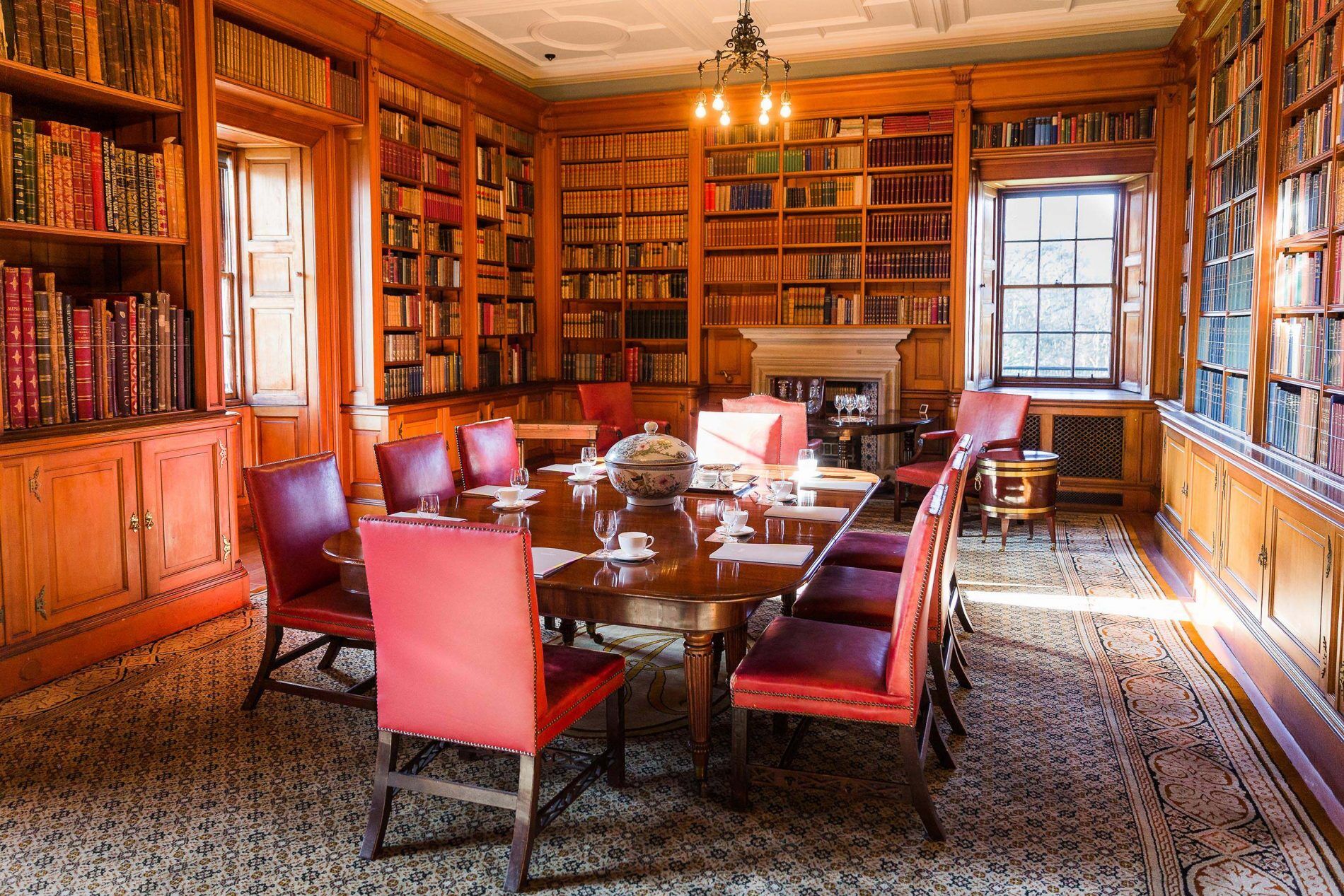 Scottish Library at Barnbougle Castle with wooden table and red leather chairs for corporate events.