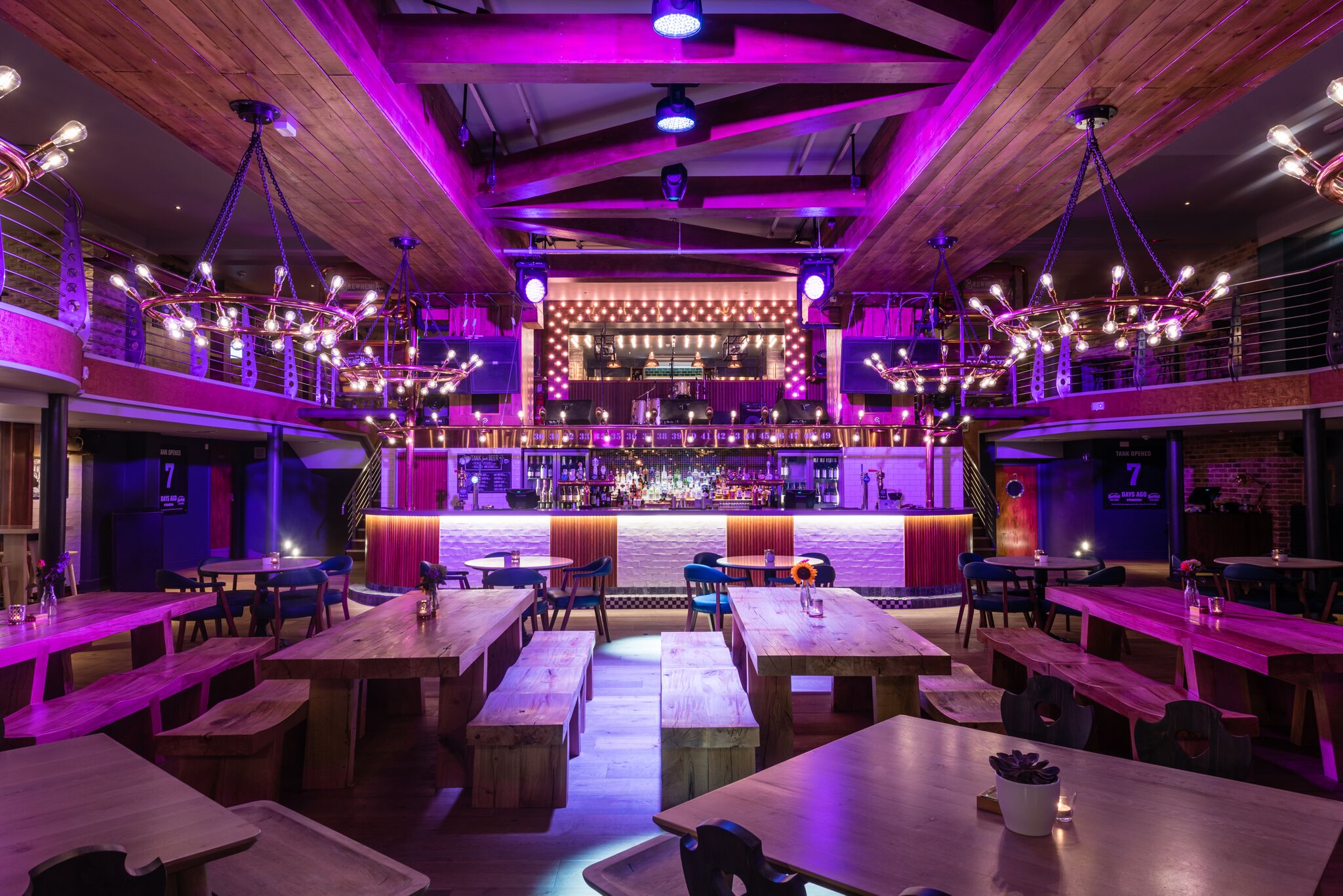 Contemporary Beer Palace event space with communal seating and vibrant purple lighting.