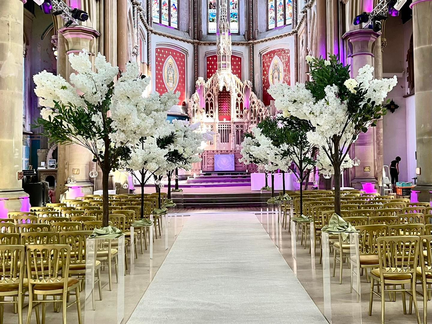 Wedding ceremony setup in The Great Nave, Manchester Monastery with floral trees and chiavari chairs.