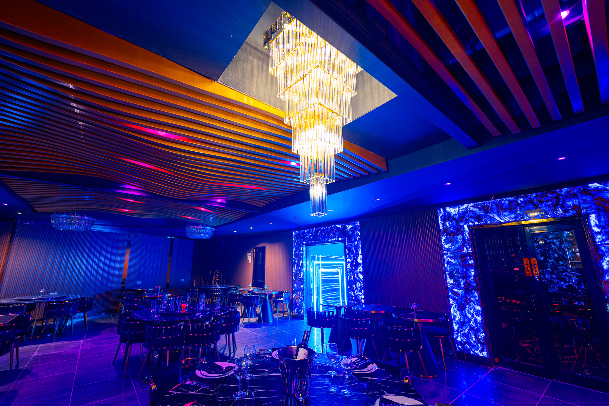 Modern event space with elegant decor and chandelier, perfect for gatherings and celebrations.