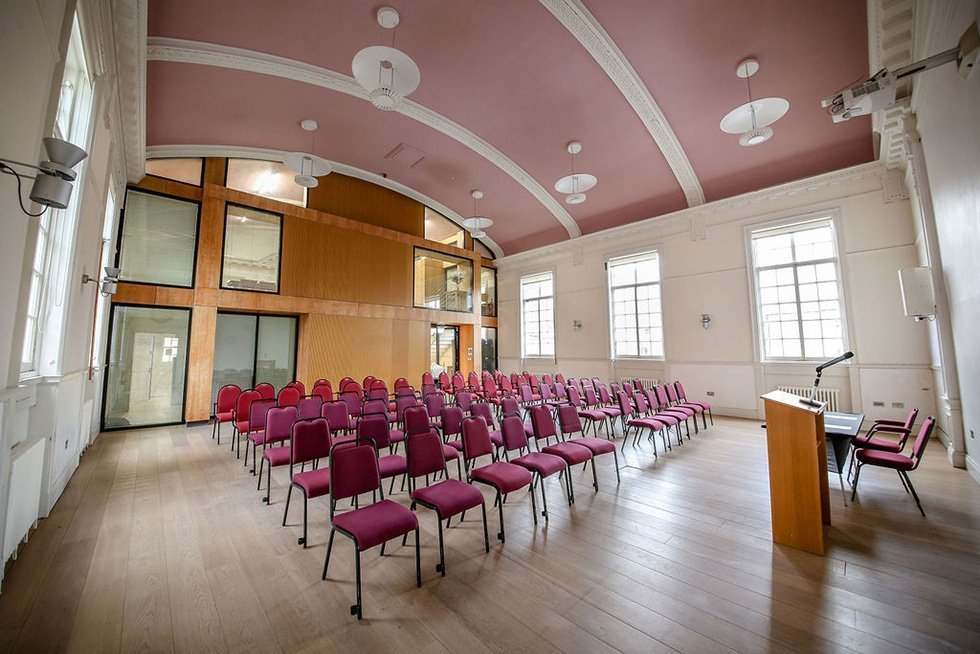 Versatile breakout room with red chairs, ideal for workshops and presentations.