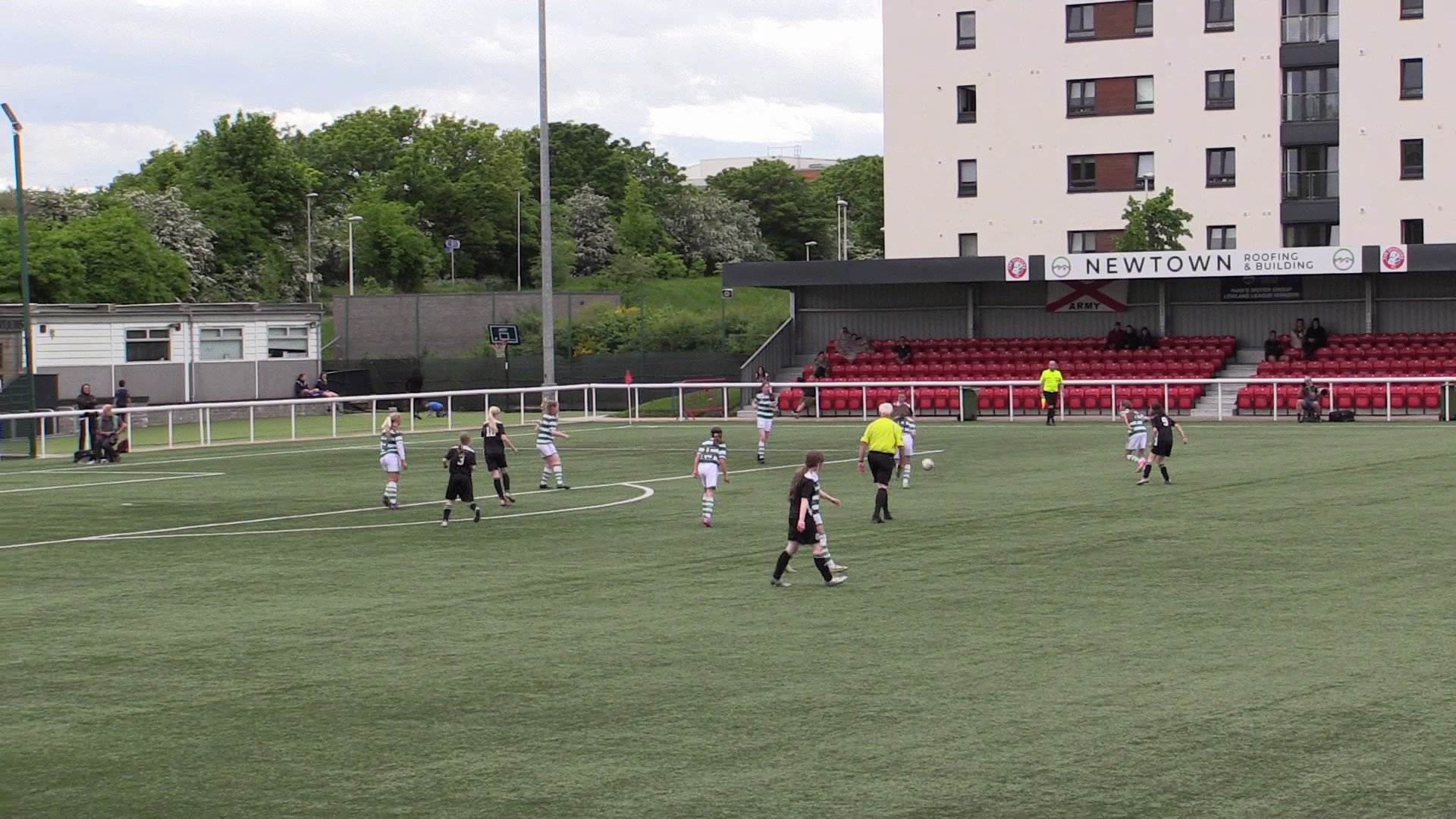 Newtown Roofing and Building Stand at Ainslie Park Stadium during a vibrant sports event.