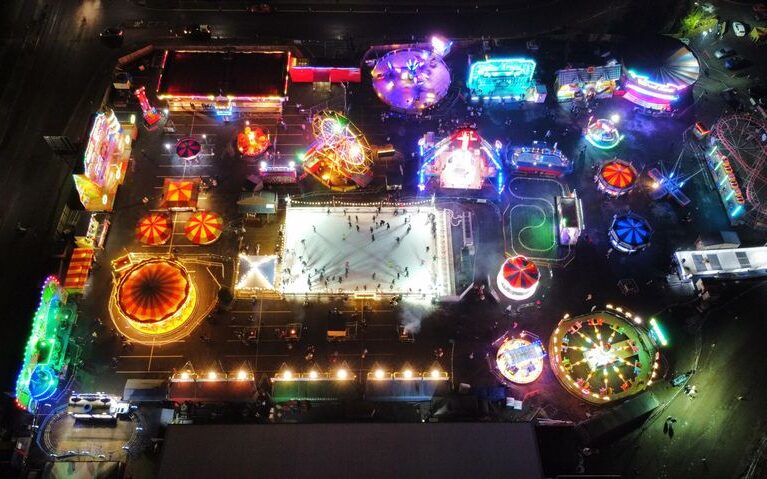 Illuminated Rainton Arena Conference Centre with carnival rides and ice skating rink.