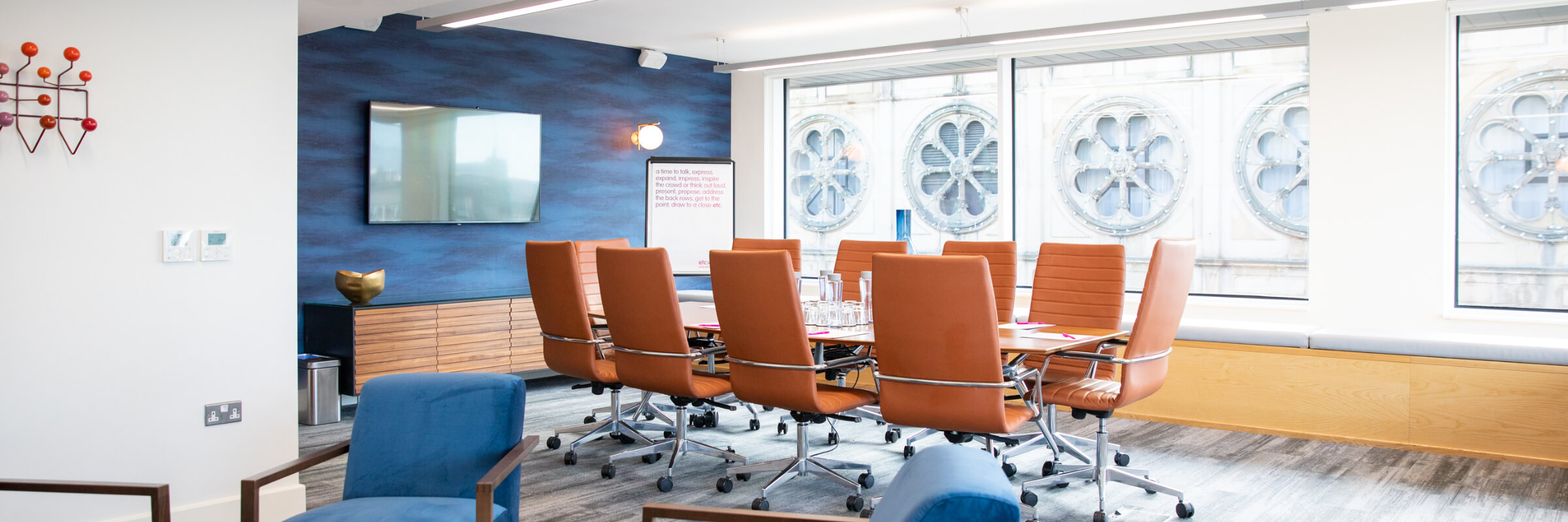 Modern conference room in Etc.venues Manchester with ergonomic orange chairs for meetings.