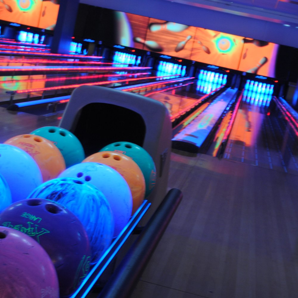 Indoor bowling alley with neon lights, ideal for team-building and corporate events.