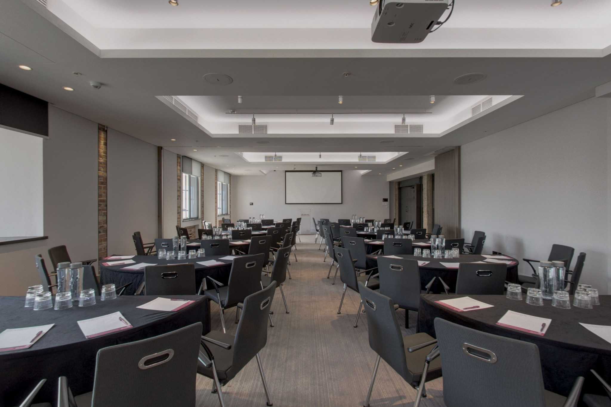 Chancellor Suite at etc.venues County Hall: modern meeting space with round tables for events.