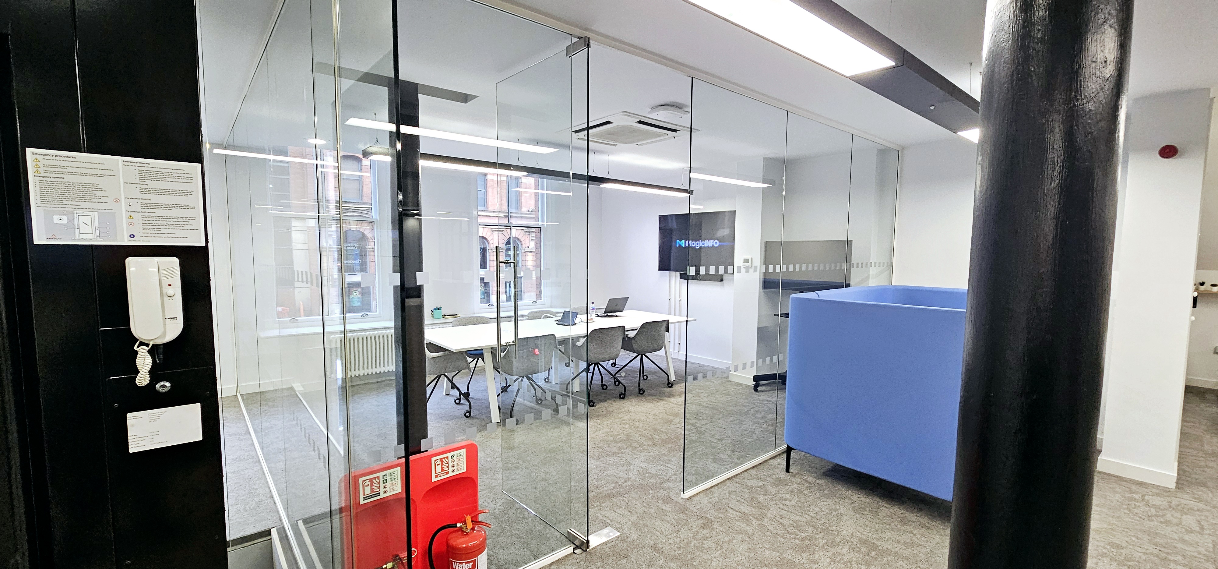 Modern meeting room with glass walls, blue seating for collaboration and brainstorming.
