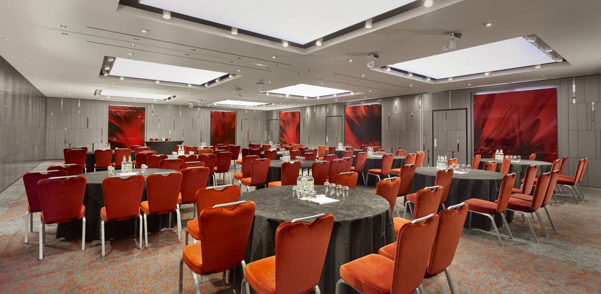 Event space at City Suites, Park Plaza London: round tables, black linens, red chairs.