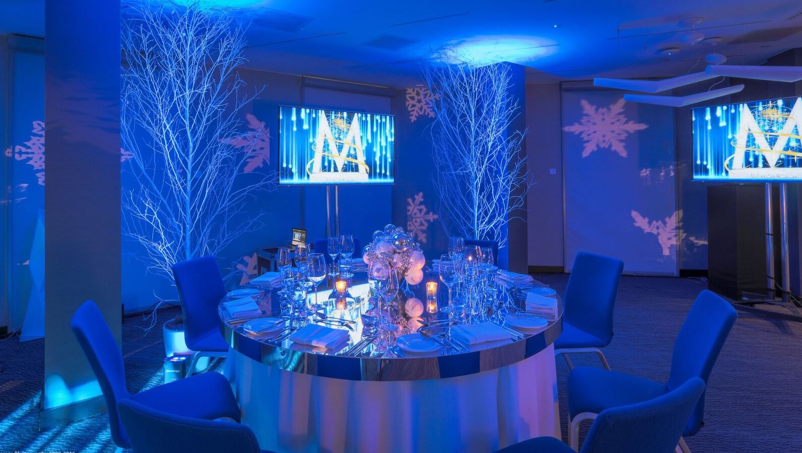 Elegant round table setup in modern event space for winter gatherings.