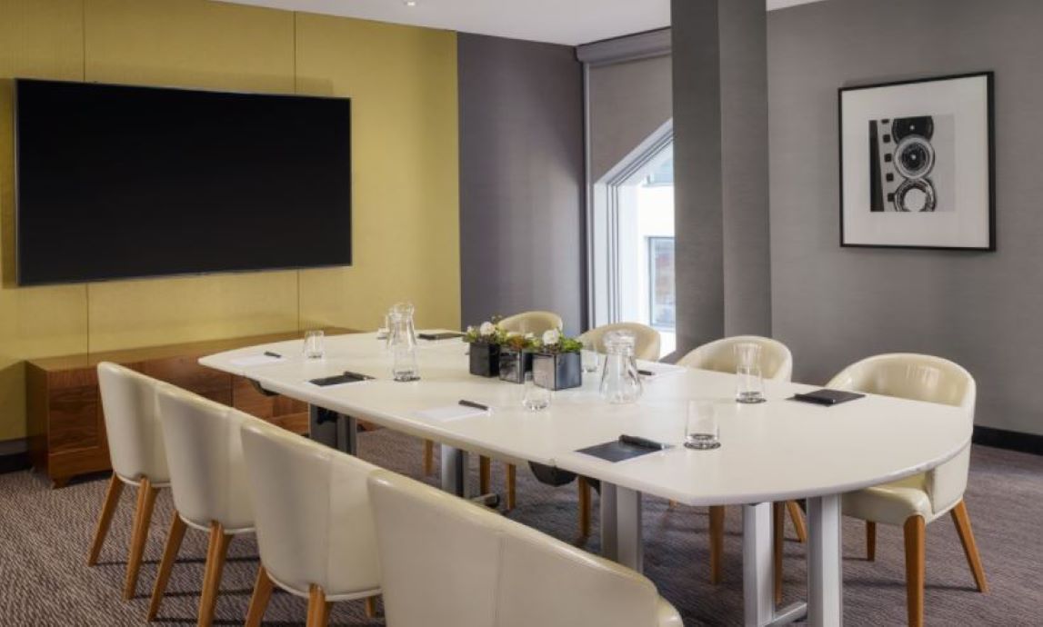 Modern meeting room with sleek table, ideal for corporate workshops and presentations.